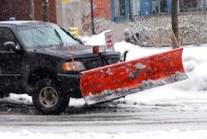 Snow plow truck on a road during a snowstorm